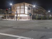 an empty street is lit up at night, including traffic light, sidewalk and building