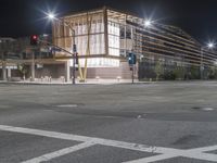 an empty street is lit up at night, including traffic light, sidewalk and building