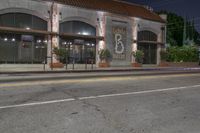 an empty street at night with a stoplight and two parked cars in front of it