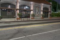 an empty street at night with a stoplight and two parked cars in front of it