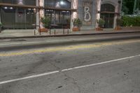 an empty street at night with a stoplight and two parked cars in front of it