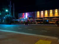 a street is empty in front of a colorful store at night time with bright lights