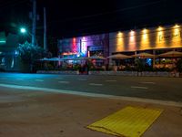 a street is empty in front of a colorful store at night time with bright lights