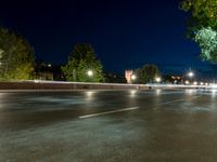 an empty street at night, with an urban clock tower in the background behind it