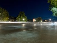 an empty street at night, with an urban clock tower in the background behind it