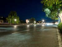 an empty street at night, with an urban clock tower in the background behind it