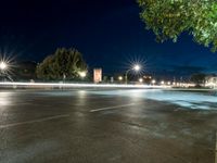 an empty street at night, with an urban clock tower in the background behind it