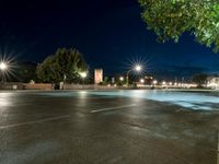 an empty street at night, with an urban clock tower in the background behind it