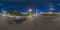 a full view of an empty street at night time with the city lights in the background