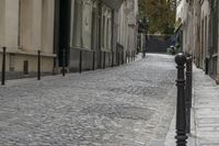 the street is empty in the middle of an old town with cobblestones, wrought bars and buildings