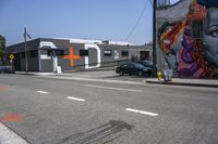 an empty street that has several paintings and graffiti on it on the sidewalk of a city street