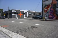 an empty street that has several paintings and graffiti on it on the sidewalk of a city street