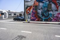 an empty street that has several paintings and graffiti on it on the sidewalk of a city street