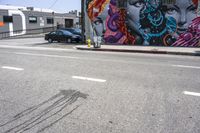 an empty street that has several paintings and graffiti on it on the sidewalk of a city street