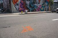 an empty street that has several paintings and graffiti on it on the sidewalk of a city street