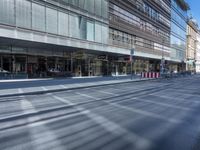 a street is empty, with cars parked in the sun on both sides of the road