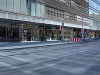 a street is empty, with cars parked in the sun on both sides of the road