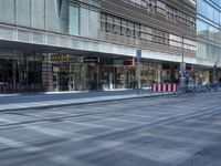 a street is empty, with cars parked in the sun on both sides of the road