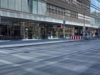 a street is empty, with cars parked in the sun on both sides of the road