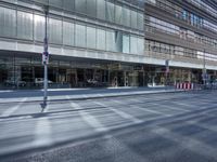 a street is empty, with cars parked in the sun on both sides of the road