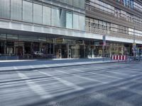 a street is empty, with cars parked in the sun on both sides of the road