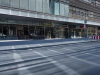 a street is empty, with cars parked in the sun on both sides of the road