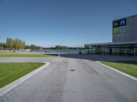 an empty street and parking lot with the sky in the background behind it, as people walk by