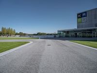 an empty street and parking lot with the sky in the background behind it, as people walk by