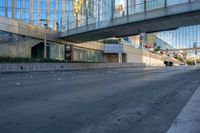 a view of an empty street with a pedestrian bridge over it in the background and skyscrapers