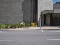 an empty street in front of some buildings and flowers in the corner of the street