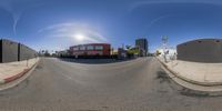 a panoramic photograph of an empty street at the edge of the road with a red building behind it