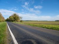 an empty street near the side of a wide road in the country side of a farm land