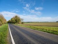 an empty street near the side of a wide road in the country side of a farm land