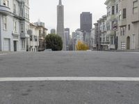 an empty street in front of tall buildings and skyscrapers in the background as seen from near the edge of the road
