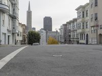 an empty street in front of tall buildings and skyscrapers in the background as seen from near the edge of the road