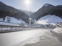 an empty street is shown with no cars on it in the middle of the snowy mountain