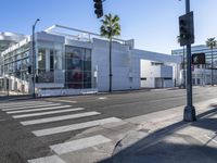 an empty street with a store front and building in the distance with palm trees next to it