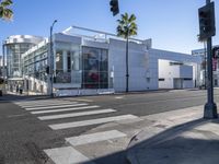 an empty street with a store front and building in the distance with palm trees next to it