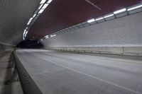 a empty street under the subway next to a long bridge with beams and large windows