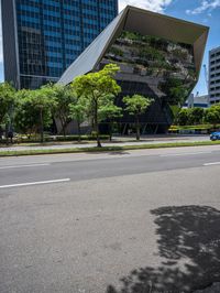 an empty street in a city with buildings and trees behind it with a water puddle