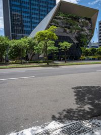 an empty street in a city with buildings and trees behind it with a water puddle