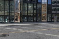 an empty street is next to a tall building that is connected by a road that goes up into the other side