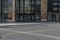 an empty street is next to a tall building that is connected by a road that goes up into the other side