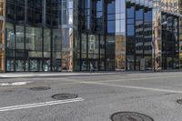 an empty street is next to a tall building that is connected by a road that goes up into the other side