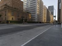 an empty city street with tall buildings and cars parked in the middle of the road