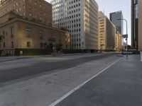 an empty city street with tall buildings and cars parked in the middle of the road