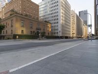 an empty city street with tall buildings and cars parked in the middle of the road
