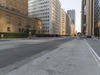 an empty city street with tall buildings and cars parked in the middle of the road