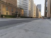an empty city street with tall buildings and cars parked in the middle of the road