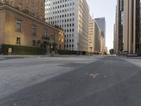 an empty city street with tall buildings and cars parked in the middle of the road